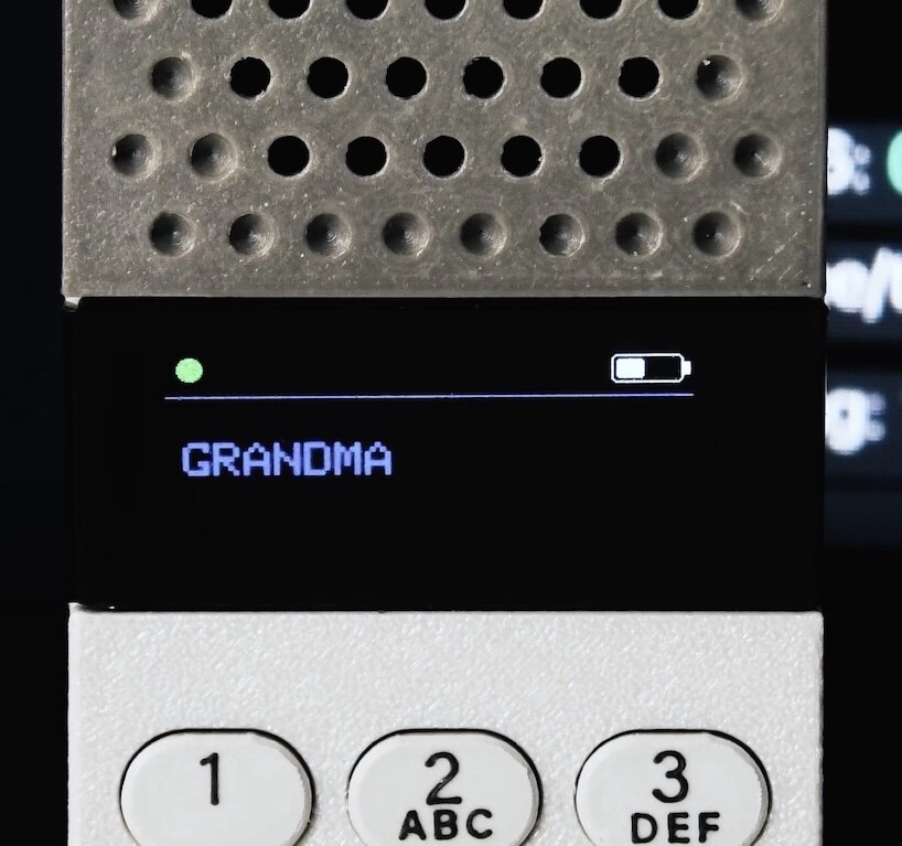 Close-up of the OLED display showing an incoming call from “GRANDMA” with battery and signal indicators