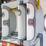 Interior view of a sectional habitat model showing airlock chambers, colourful utility conduits and access steps within a grey and white structure