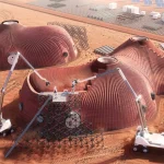 Aerial rendering of large ribbed red habitat structures under construction by robotic arms and vehicles on the Martian surface, with solar arrays in the background