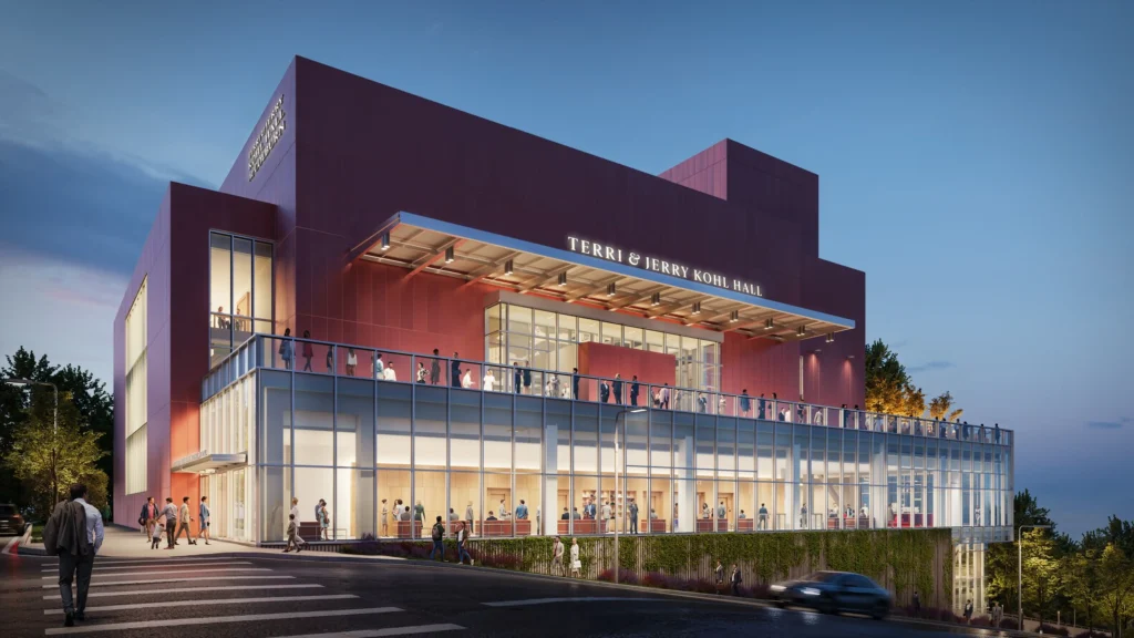Night exterior rendering of the pink Terri and Jerry Kohl Hall with glowing glass lobby and terrace