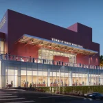 Night exterior rendering of the pink Terri and Jerry Kohl Hall with glowing glass lobby and terrace