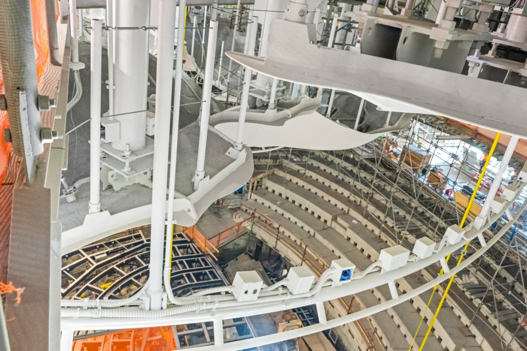 Construction interior showing white structural supports, scaffolding and the curved seating bowl under formation