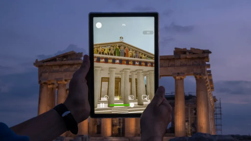 Hands holding tablet displaying 3D augmented reality reconstruction of the ancient Parthenon temple over real ruins at dusk