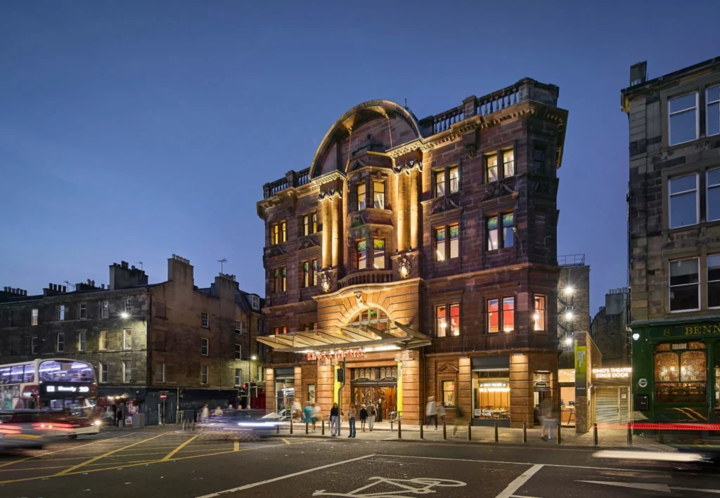 Evening street view of the King’s Theatre with traffic and pedestrians outside the glowing entrance