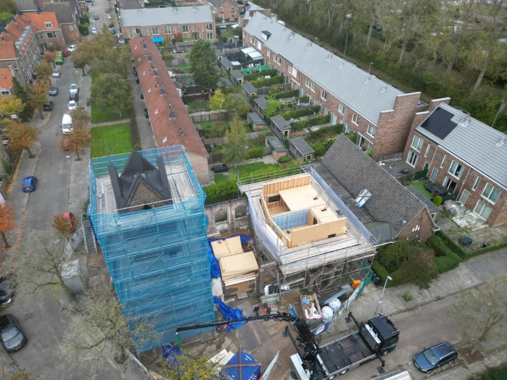 Aerial photograph of the construction site with scaffolding around the tower and timber framing of a new house