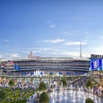 Wide view of the stadium and plaza with crowds, fountains and surrounding mixed-use buildings at dusk