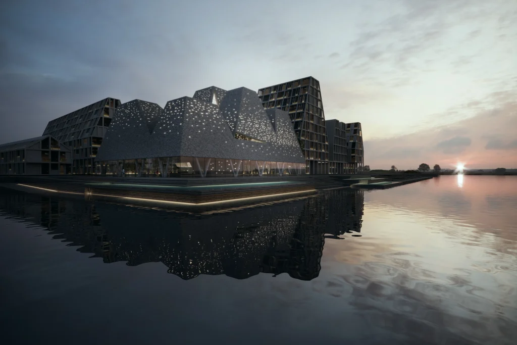 Twilight view of the illuminated KAI building reflected in calm harbour water, with surrounding architecture and a soft sunset
