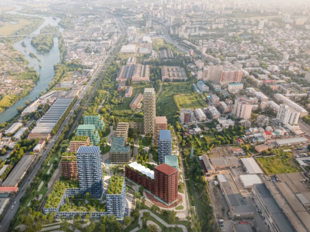 High aerial view of the complete Loco Park masterplan showing nine colourful residential buildings arranged around parks on the former industrial site