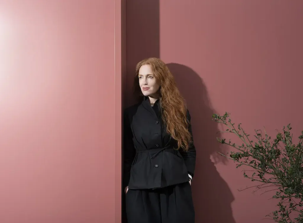 Lion Green Road Wins 2026 RIBA Stirling Prize for Dense Living_Portrait of architect Mary Duggan standing against a yellow brick wall
