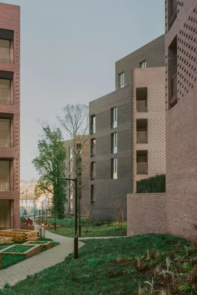 Pathway winding between the brick facades with young trees and planting beds