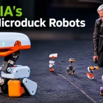 Jensen Huang kneeling on stage with a laptop while several Microduck robots stand in a line in front of him