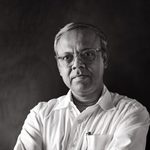 Black-and-white portrait of architect Bayejid Khondoker wearing glasses and a white shirt, arms crossed