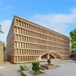 Large brick building with dense horizontal brick screening and a broad arched entrance at ground level