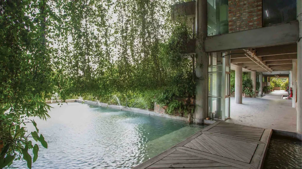 Covered walkway and reflecting pool lined with dense hanging greenery at the Green Field Factory