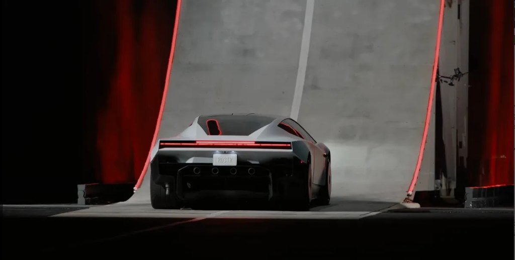 Rear view of the Roadster with active wing deployed under red stage lighting