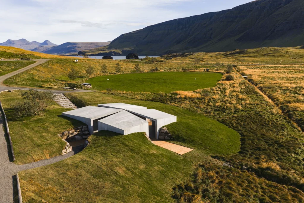Aerial view of the cross-shaped concrete Temple set into green and golden hillside near a lake