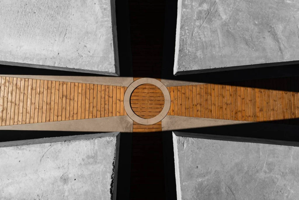 Close overhead detail of the wooden Celtic-cross floor meeting at a circular center under concrete edges