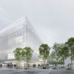 Angular view of the tall translucent gridded façade rising above a paved public space lined with trees