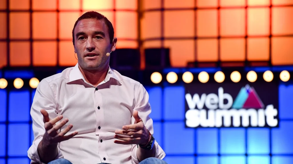 Kevin Weil speaking on stage at Web Summit, gesturing with both hands while wearing a headset microphone