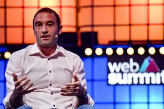 Kevin Weil speaking on stage at Web Summit, gesturing with both hands while wearing a headset microphone
