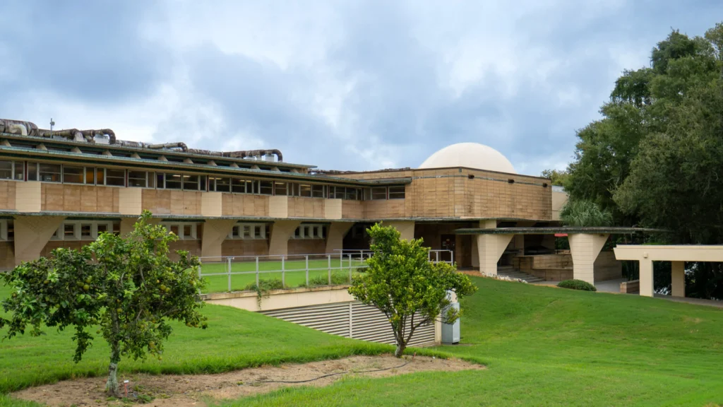 Upper exterior of the planetarium showing the dome rising above patterned concrete panels and a central brick pier