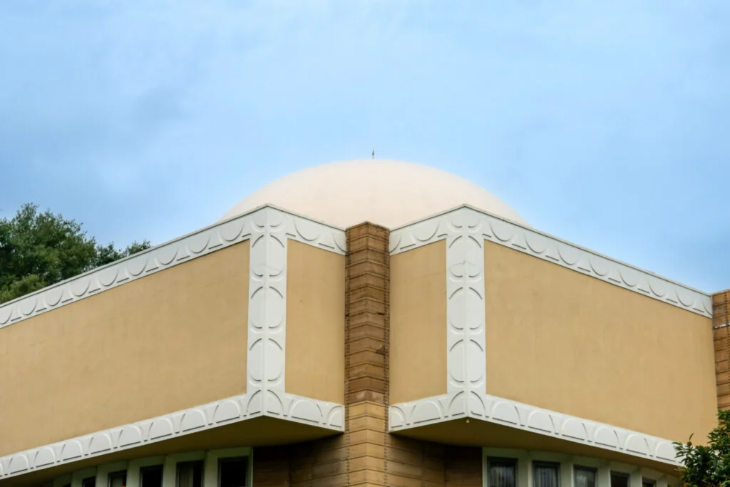 Low-angle view looking up the corner of the building with patterned textile blocks and a vertical masonry pier against the sky