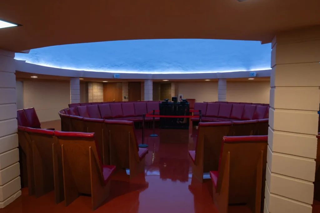 Circular interior of the restored planetarium with red vinyl seating arranged around a central projector under a blue-lit dome