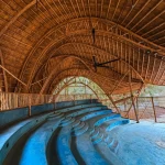 Interior of the auditorium showing blue tiered seating under a soaring bamboo vaulted ceiling