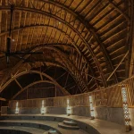 Warmly lit interior of the bamboo auditorium with tiered seating and decorative wall lights