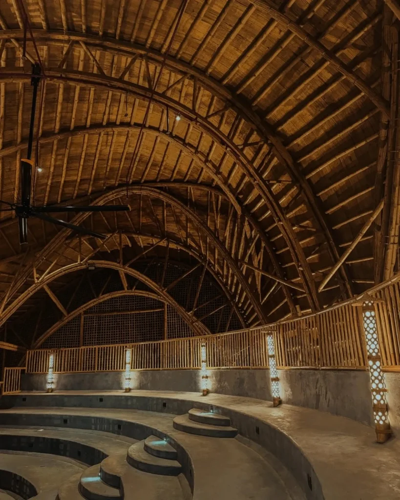 Warmly lit interior of the bamboo auditorium with tiered seating and decorative wall lights