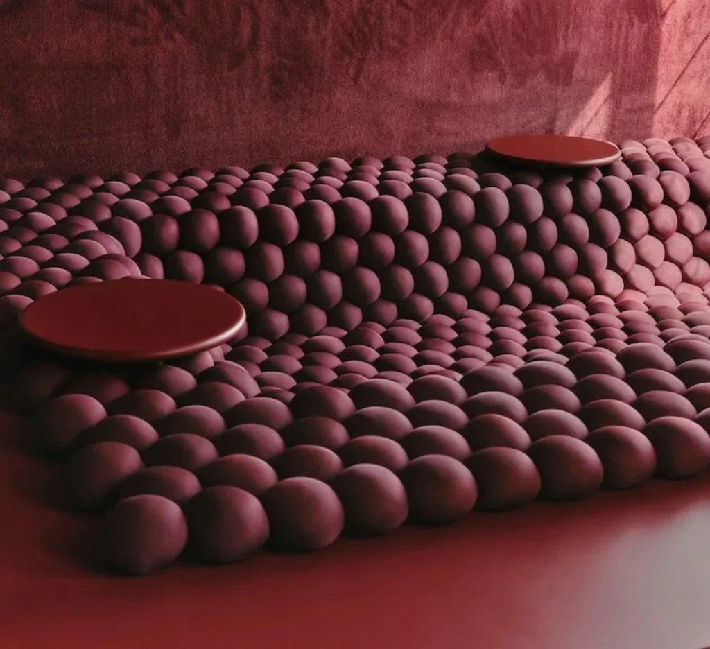 Soft undulating field of deep maroon rounded forms with two flat circular platforms resting on top