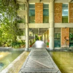 Person walking along a wooden path through a water-filled courtyard inside the factory