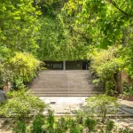 Wide concrete staircase leading up into a densely planted green hillside entrance
