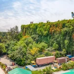 Aerial view of the factory’s living green wall covered in dense vegetation beside a tree-filled compound