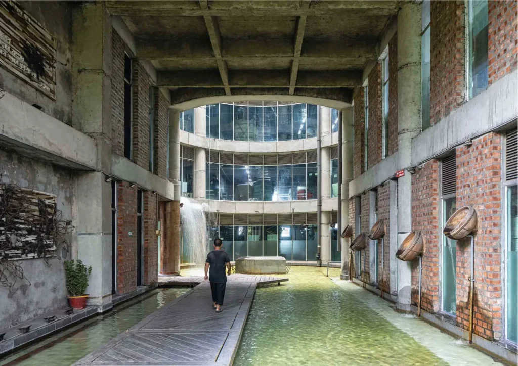 Person walking along a wooden path through a water-filled courtyard inside the factory