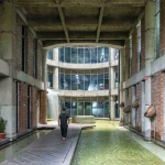 Person walking along a wooden path through a water-filled courtyard inside the factory