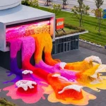 Aerial view of multicoloured LEGO flower waves cascading from the TANK Shanghai building onto the paved plaza