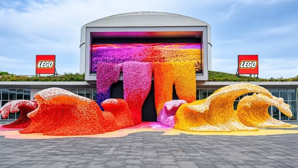 Front view of large LEGO flower wave sculptures in red, orange, yellow and purple standing before the TANK Shanghai facade
