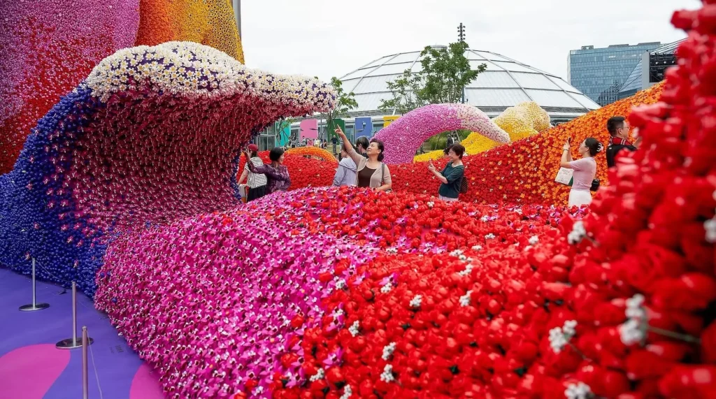 Visitors photographing and walking among sweeping pink, red and blue LEGO flower installations