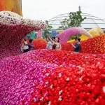Visitors photographing and walking among sweeping pink, red and blue LEGO flower installations