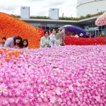 Families and visitors examining a wide field of pink LEGO roses with larger orange and purple waves in the background