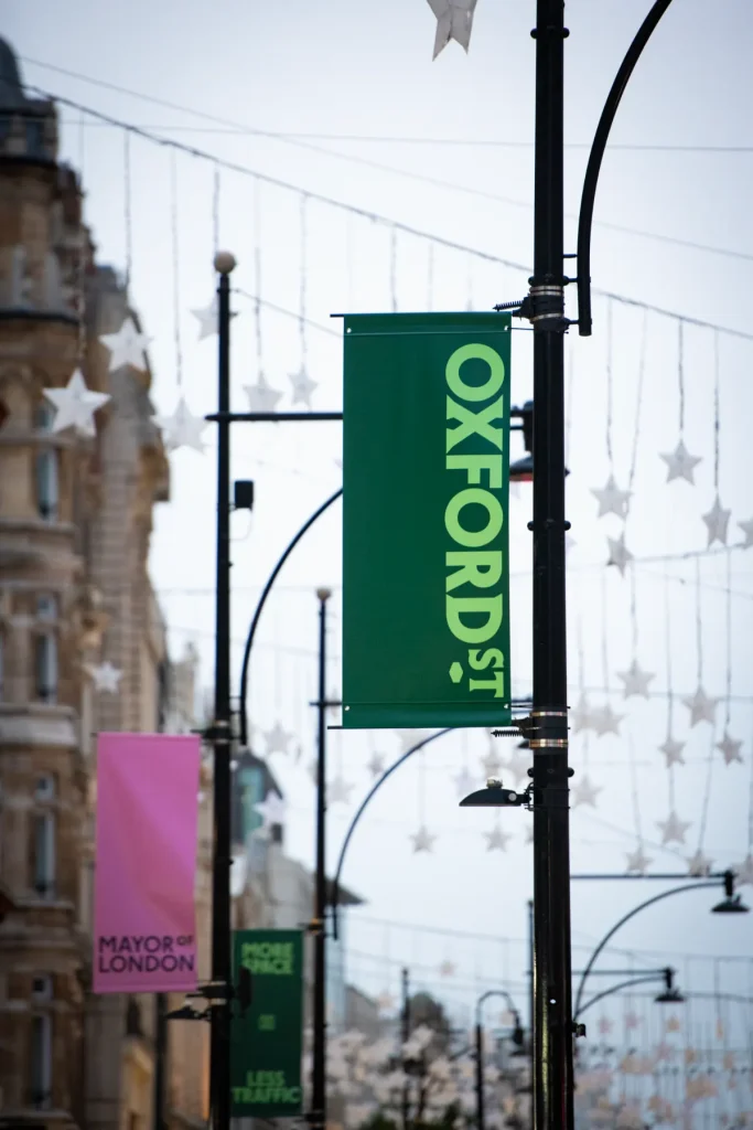 Close-up of an Oxford Street banner in London, surrounded by hanging Christmas star decorations as the famous shopping street prepares for pedestrianization