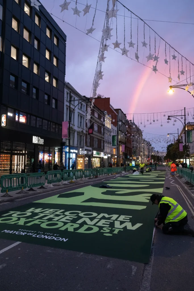 Workers install green Welcome to the New Oxford Street graphics on the road in London, marking an early stage of the Oxford Street pedestrianization initiative