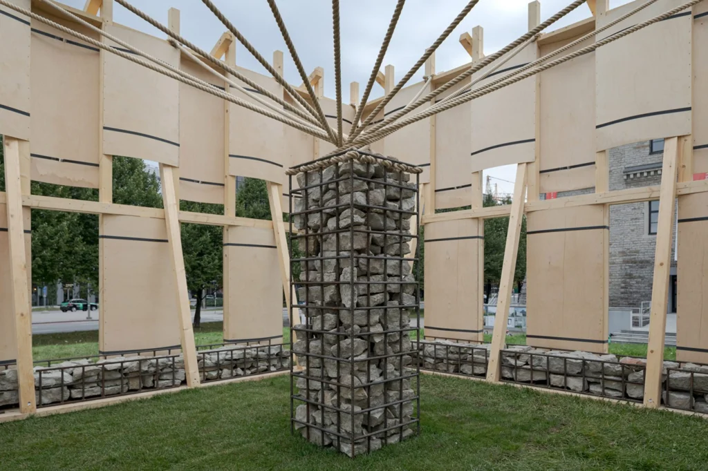 Interior view of the pavilion showing the central limestone-filled rebar column with ropes radiating outward to the timber frame