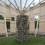 Interior view of the pavilion showing the central limestone-filled rebar column with ropes radiating outward to the timber frame