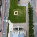 Bird’s-eye view of the square Resonance Pavilion centred on a grassy island surrounded by roads and the museum roof