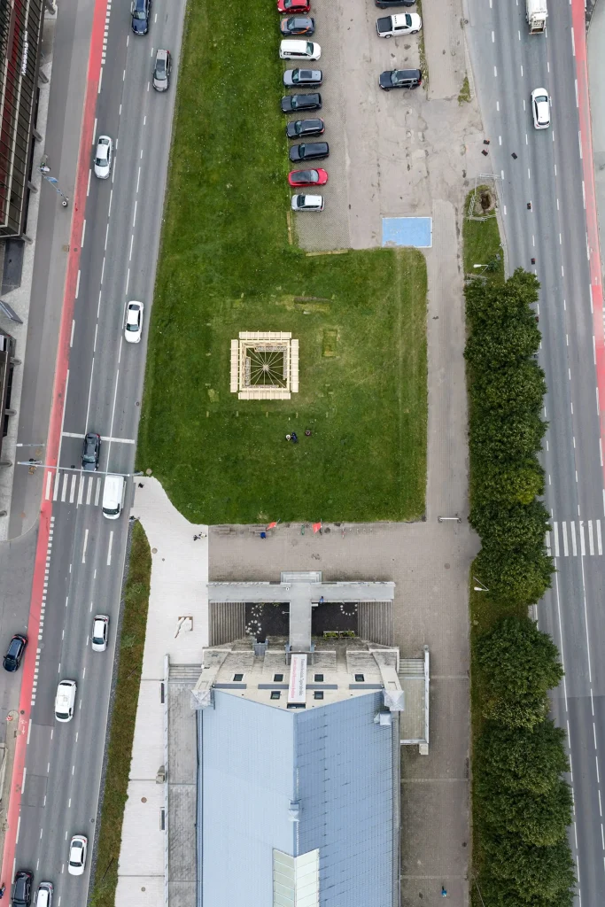 Bird’s-eye view of the square Resonance Pavilion centred on a grassy island surrounded by roads and the museum roof