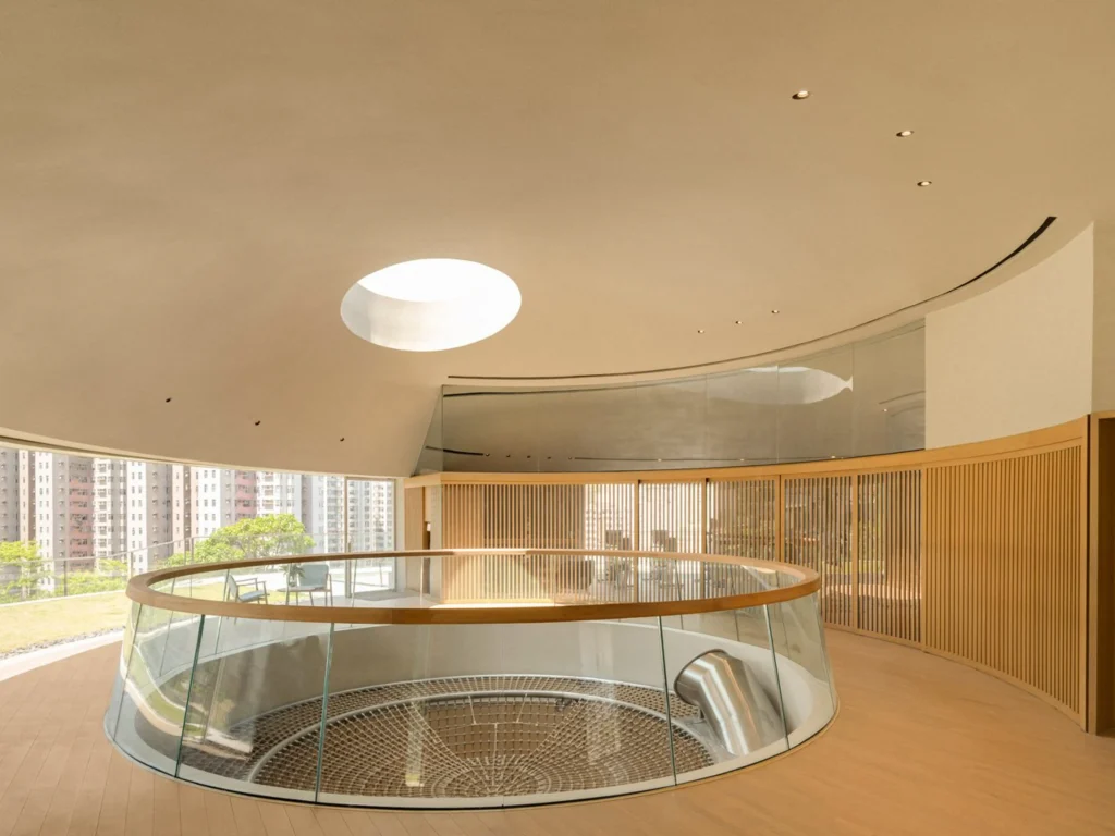 Upper-level circular gallery with glass balustrade overlooking the climbing net and a central skylight