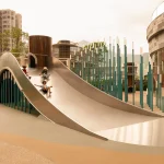 Children sliding down a large curved stainless-steel slide in the outdoor playground
