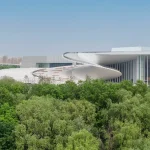 Exterior view of the Shanghai Grand Opera House’s white helical roof rising above dense green trees